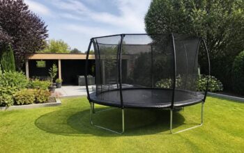 Trampoline met veiligheidsnet in een verzorgde achtertuin